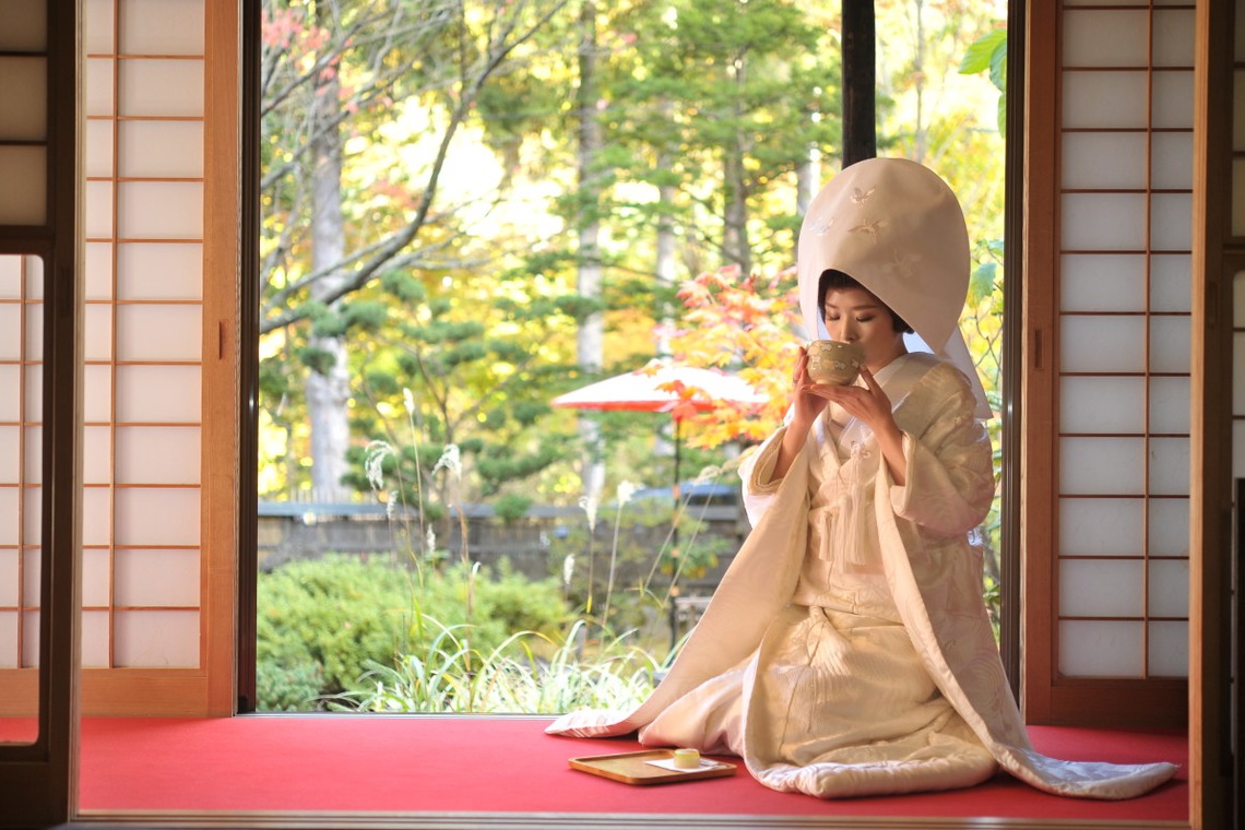 Lady in Shiromuku drinking tea next to a garden