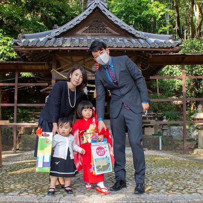 辻 充彦が出張撮影した屋外用家具, 荷物とバッグ, ベンチなどが写った「七五三」の家族写真