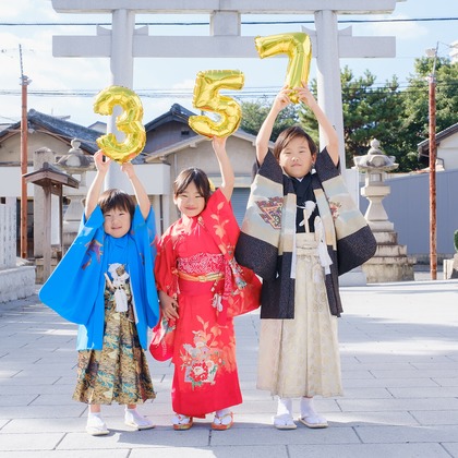 高夏写真店が出張撮影した荷物とバッグ, ジェスチャー, ショートパンツなどが写った「七五三の撮影」の家族写真