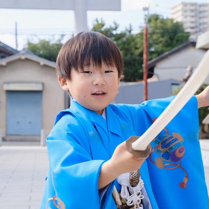 高夏写真店が出張撮影した荷物とバッグ, ジェスチャー, ショートパンツなどが写った「七五三の撮影」の家族写真